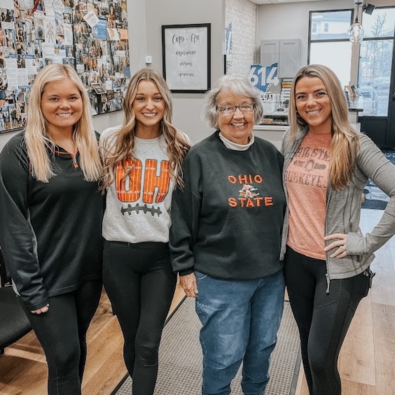Group of three patients smiling inside a chiropractic clinic, representing a supportive wellness community visit.