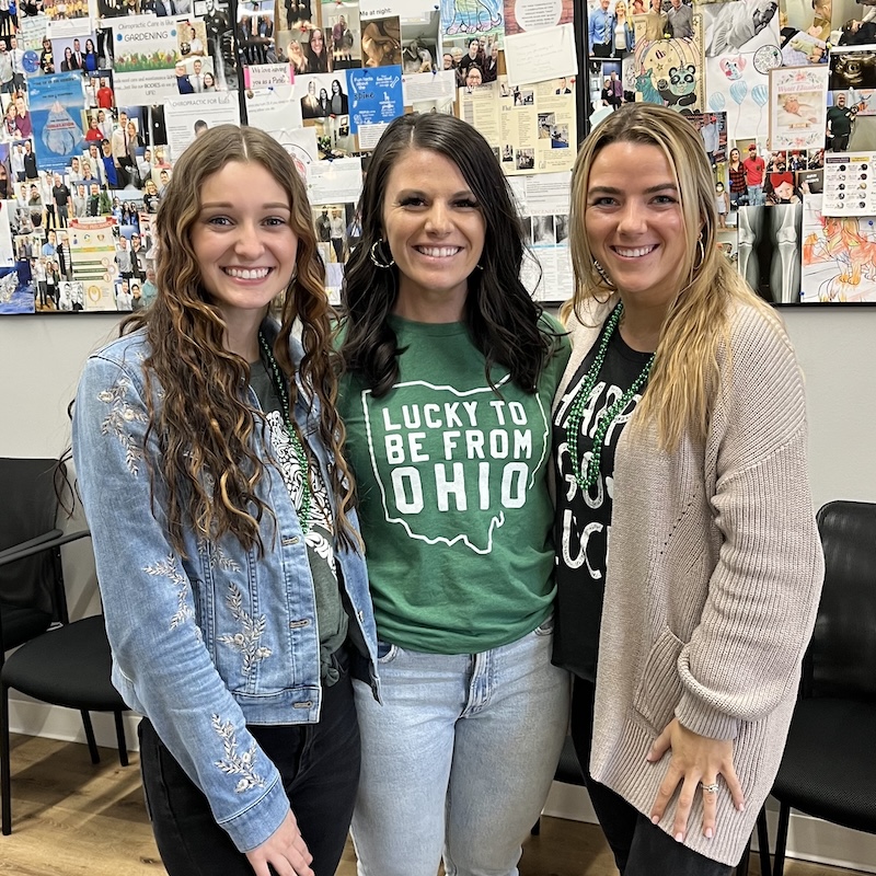 Three women posing together at a chiropractic office, highlighting a patient appreciation or wellness visit.