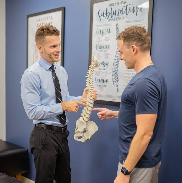 Dr. Nicholas Esser showing male patient a spine model