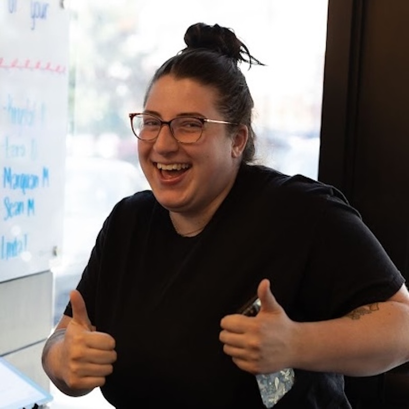 Patient smiling and giving a thumbs-up inside a chiropractic clinic, indicating relief and positive results from care.